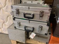 Photo showing four stacked metal carrying cases of two different sizes with foam interiors and metal latches, some with Sirius branding on the handles.