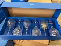 Four blue boxes each holding 6 crystal goblets with silver rims, arranged in two rows in their packaging.