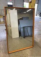 Full front view of the rectangular mirror with wooden frame showing its size and shape.
