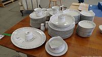 Photo showing most dinnerware stacked including cups, saucers, plates, platter and salt and pepper shakers.