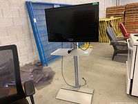 Front view of Samsung TV on stand with remote on white shelf