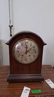 Full view of vintage wooden mantel clock with metal framed glass clock face.