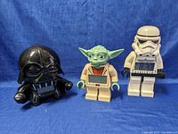 Photo showing all three Star Wars character clocks: Darth Vader, Yoda, and Stormtrooper against a blue background.