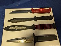 Photo showing four cutting utensils with different blade styles and handles laid out on white background