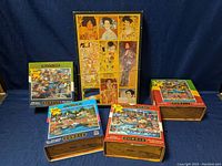 Five jigsaw puzzles displayed, including one Gustav Klimt art puzzle and four Dowdle brand puzzles with Canadian themed art.