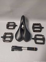Top view of black bike seat, five plastic pedals surrounding it, and mini hand pump below
