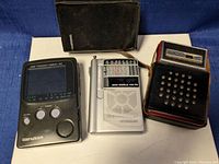Photo showing front view of Genexxa Pocketvision 30 mini TV, Grundig 100 PE radio, and Republic 8 transistor radio with cases