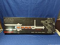 Photo of the full boxed baton with illuminated segments and Star Wars branding on black background box