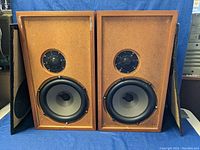 Front view of the pair of vintage bookshelf speakers without grilles, showing large woofers and tweeters in wood cabinets.