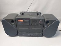 Front view of Yamaha YST-C11 boom box with attached speakers, showing radio display, cassette deck, and CD player with lid closed.