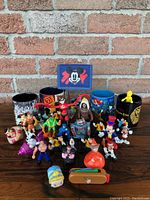 Photo showing multiple Disney character figurines and three ceramic Disney mugs arranged on table