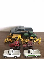 Photo showing all nine vehicles: gray pickup, green tractor, two yellow backhoes, two red tractors, two white pickup trucks