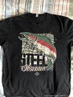 Black fishing shirt featuring a large colorful graphic of a steelhead trout jumping and text 'Steel Obsession' with LRS logo.