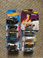 Photo of 10 Hot Wheels cars in original packages, various models and colors including black, white, Disney Aladdin themed car