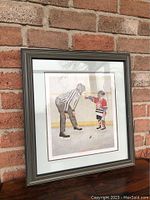 Full view of framed print showing the artwork of a referee and young hockey player in ice rink setting.