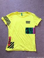 Front view of the yellow Piazza Italia motor racing T-shirt showing all graphics including black stripes on right sleeve, START and number 46 blocks on front lower side.