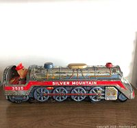 Side view of the vintage tin toy train 'Silver Mountain' showing mechanical details and figure in cab.