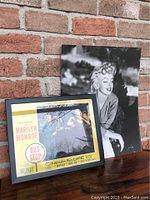 Larger black and white Athena International 1992 Marilyn Monroe poster showing her smiling, placed behind lobby card for size comparison.