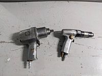Top-view of both air tools on a grey surface showing the size difference and general condition.