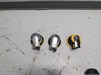 Three palm sanders laid out horizontally, showing the top and sanding pads. Yellow and black color, showing wear and some missing fittings.