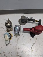Top-down photo showing five air sanders arranged on a floor surface including a red-handled sander, a black-handled sander, and three others in varying conditions.