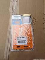 Front view of sealed Fiskars Card Boss embossing stencil packaging, showing orange stencil sheet with white cut-out designs and product label.