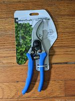 Front view of Garant by-pass pruner in original packaging with blue handles and visible curved cutting blades for pruning
