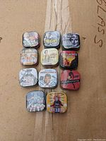 Top-down view of all 11 sealed collectible mint tins arranged in a grid, showcasing their colorful and distinct vintage-style designs and themes.