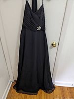 Front view of the black floor-length bridesmaid dress with halter neck, ruched bodice, and brooch detail on the waist