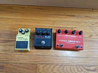 Overview of three pedals on wood surface: Boss SD-1 (yellow), ProCo Turbo RAT (black), Fulltone Full-Drive 2 (red)