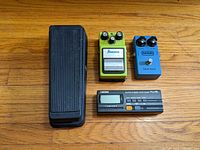 Top-down view of all four devices arranged on wood floor: Cry Baby wah pedal, Ibanez SD9, MXR Blue Box, Boss TU-70 tuner.