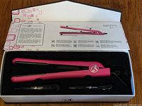 Pro Cabello hair straightener in box showing hot pink iron with two black clips and packaging insert.