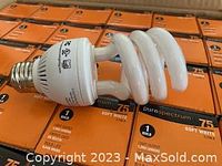 Close-up of compact fluorescent light bulb and packaging labeled 75 watt soft white Pure Spectrum.