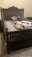 Black queen bed fully assembled with mattress and bedding shown for reference.