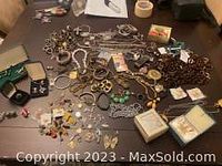 Overview photo of the entire jewelry lot laid out, showing mixed necklaces, bracelets, rings, earrings, and other jewelry pieces