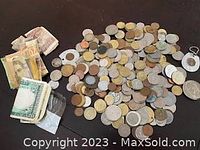 Overview of the lot showing a large pile of foreign coins and several stacks of assorted paper currency of various countries and denominations.
