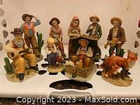 Full view of seven Homco figurines showing man playing guitar, seated boy and dog, woman, cowboys, and fox pair