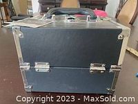 Front and side view of black makeup train case with metal corners and locking clasp