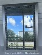 Photo of the silver framed mirror outdoors reflecting sky and landscape
