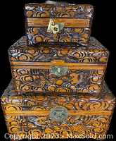 Three graduated size carved lacquered wooden boxes stacked, showing exterior carved bird and cloud patterns with metal latch closures.