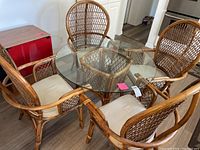 Overhead view of round glass table with four cane chairs arranged around it.