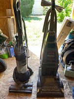 Photo of the Hoover SteamVac carpet cleaner alongside the Dyson DC25 Animal Ball vacuum cleaner showing overall condition and design