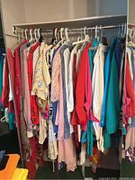 Closet filled with assorted women's clothing items hung on hangers showing variety of colors and styles