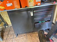 Front view of Craftsman workbench showing five drawers and cabinet door with metal finish and some contents inside.