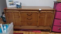 Full front view of the wooden dresser showing two cupboards and three drawers with a medium wood finish and metal handles.
