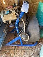 Side view showing the blue metal stand, handle, and coiled cable on the plumbing snake.