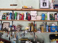 Wide view of shelves with cleaning products including sprays, cans, paper towels, and plastic bags.
