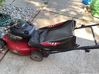 Side view of red Toro lawn mower with black grass collection bag, showing the deck and wheels.