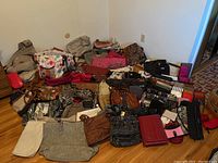 Photo of over 50 assorted purses, wallets, and bags arranged on floor, showing a variety of styles and colors.