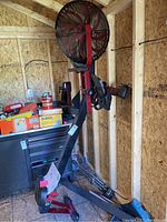 Full side view of Stamina X Air Rower inside wooden shed showing frame, seat, fan wheel and footrests